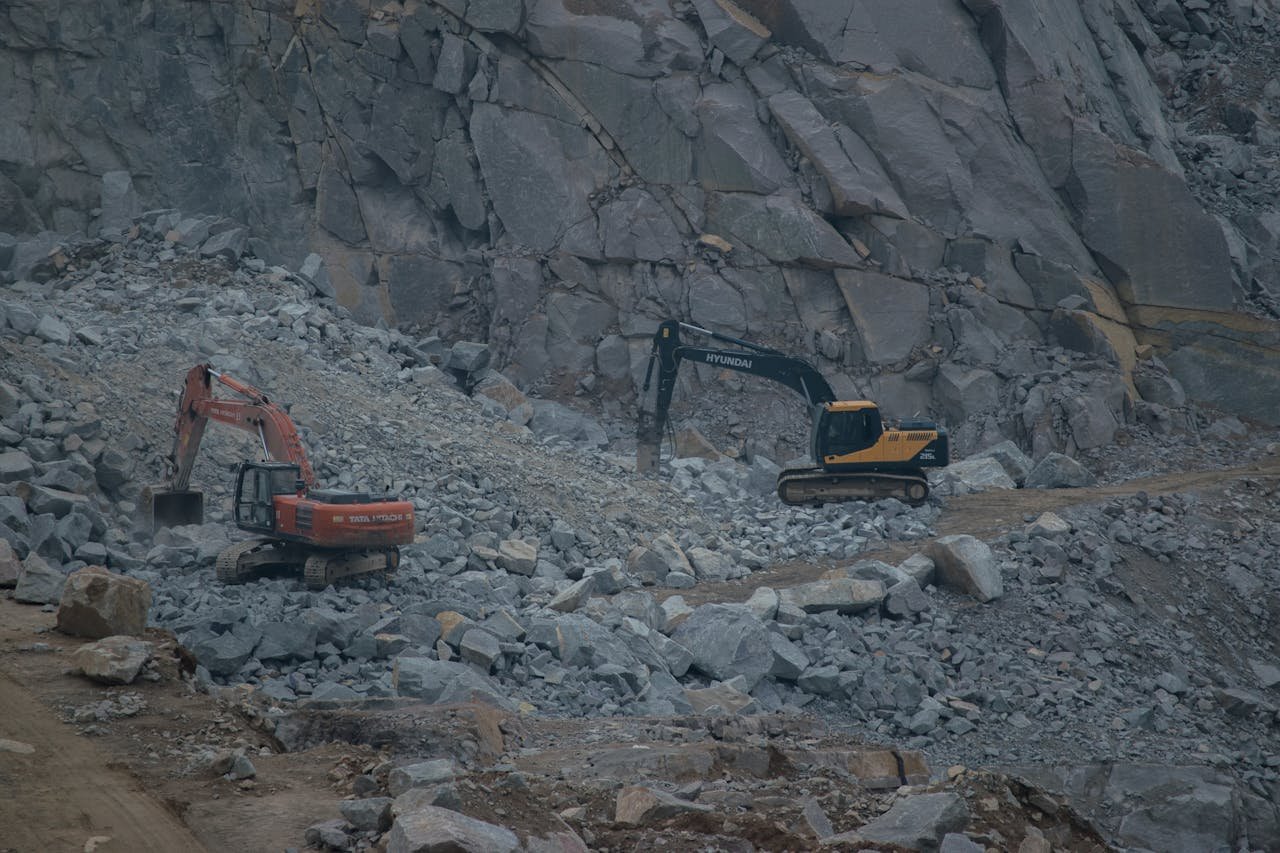 service-02 Dynamic construction site featuring excavators working on rocky terrain.